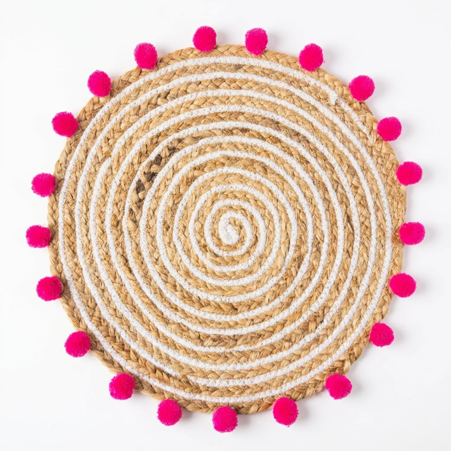 Avani Jute Weave Mat, Rosy colourway — round jute mat with hot pink pompom trim, on a plain background.