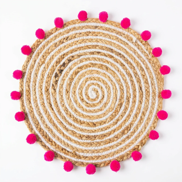 Avani Jute Weave Mat, Rosy colourway — round jute mat with hot pink pompom trim, on a plain background.