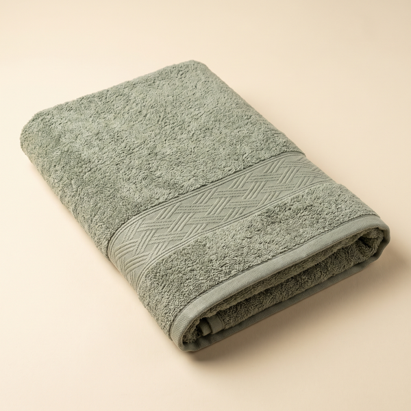 Bamboo Bath Towel 550 GSM in Sage Green, folded flat on a cream background, showing the plush terry and woven border.